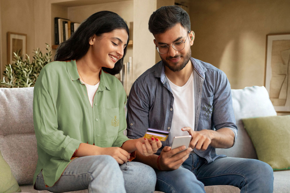 Casal jovem em Portugal a comparar crédito pessoal online num smartphone, com cartão bancário na mão, a analisar uma proposta de empréstimo.